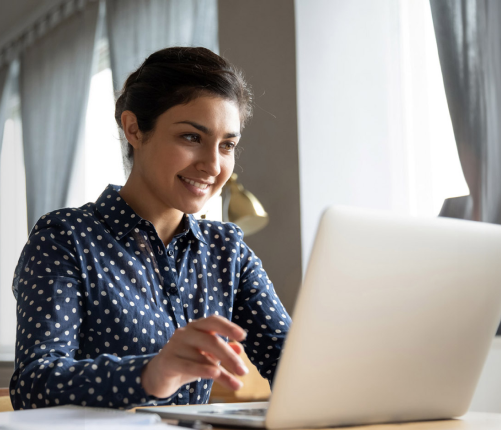Woman smiling at laptop screen.